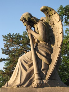 A stone statue of the winged god kneeling in park